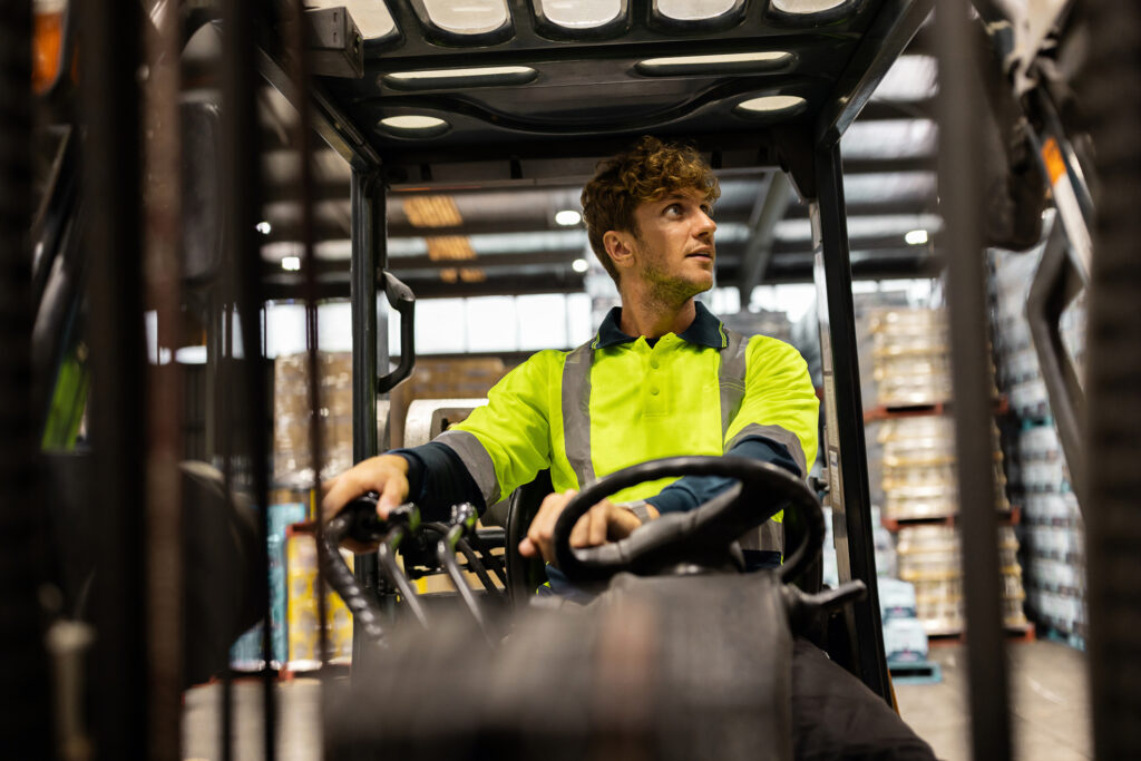 Ein Arbeiter in einem Warnschutzhemd bedient einen Gabelstapler